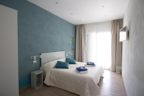 Un dormitorio con una cama con paredes azules y una ventana en un posto al sole, en Molino Nuovo