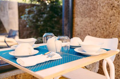 a table with white dishes and wine glasses on it at Casa das Mourôas in Mondim de Basto