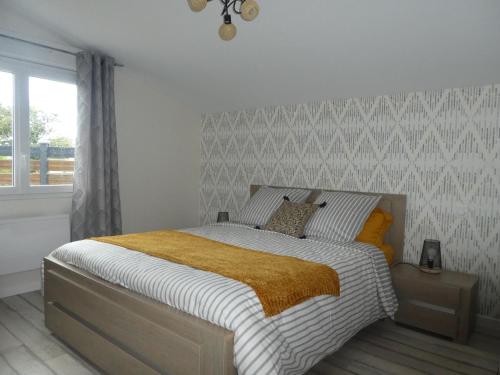 une chambre avec un lit avec une couverture jaune dans l'établissement Gîte de la forge, à Trélévern