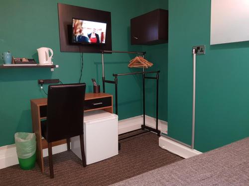 a room with a desk and a tv on a green wall at Robin 7 Lodge City Centre in Nottingham