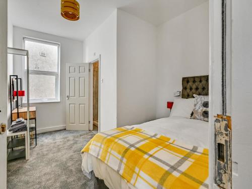 a bedroom with a yellow and white bed and a window at Albert View Rooms in Manchester