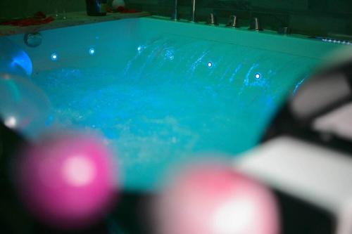 - une piscine avec des boules roses dans l'eau dans l'établissement Arty room JACCUZI & SPA CENTRE VILLE HAUT DE GAMME, à Mulhouse