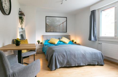 a bedroom with a bed with blue pillows and a desk at Spirit Apartments - Neben dem Titlis - Parkplatz in Engelberg