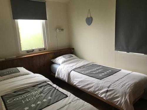 2 camas en una habitación pequeña con ventana en Groot Marquette - Noord Holland aan uw voeten en Warmenhuizen