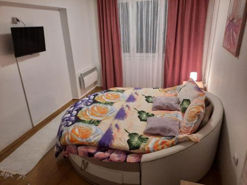 a small bed in a room with a flower blanket at Apartman Rada 2 in Bijeljina