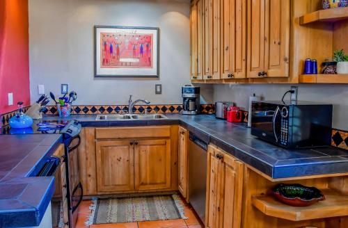 a kitchen with wooden cabinets and a microwave at Fort Marcy Suites by All Seasons Resort Lodging in Santa Fe