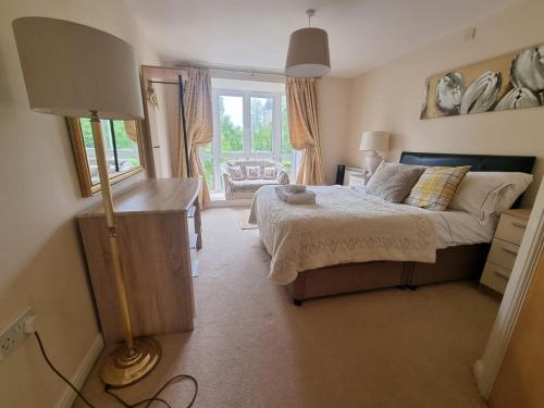 a bedroom with a bed and a lamp and a window at Sky Night Serviced Apartments in Cardiff