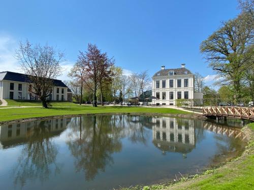a pond in front of a building with a bridge at Hotel Flora Batava in Breukelen