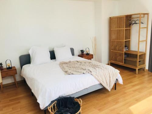 a bedroom with a bed with white sheets and wooden floors at Les charmilles in Chaudfontaine