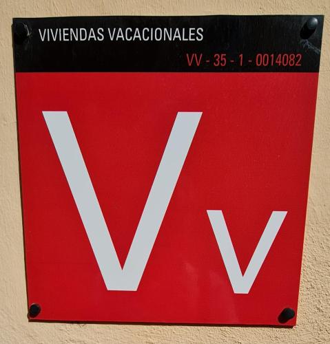 a red sign with the letter v on a wall at Casa Mamatita in Agüimes