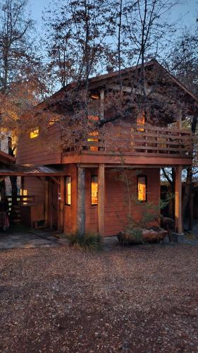 a large wooden house with a balcony on it at Cabañas Tronco Mayen in Las Trancas