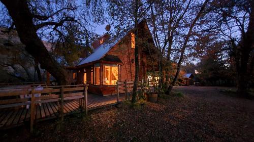 a small house with a deck with a bench in front at Cabañas Tronco Mayen in Las Trancas