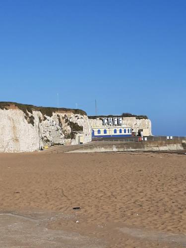 a building on the beach next to a cliff at Home from Home Stay Margate in Margate