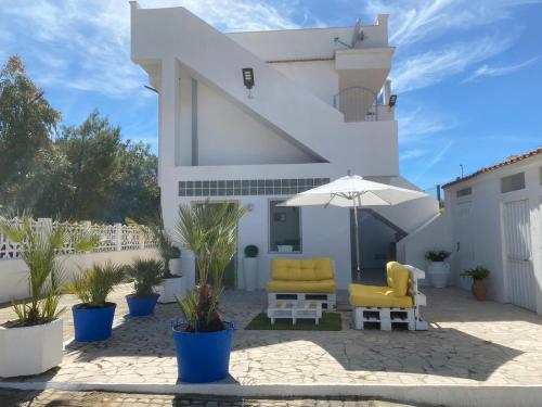 a white house with two yellow chairs and an umbrella at Puntamare Flat in Peschici