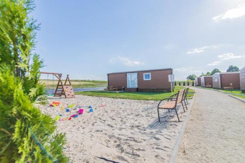 a bench on a sandy beach next to a house at Twój Zakątek pod Zatorem in Zator