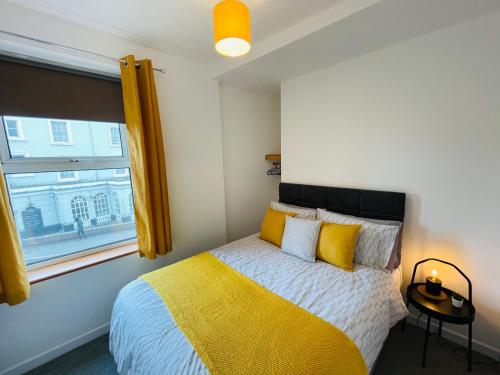 a bedroom with a yellow and white bed and a window at New North House by Staytor Accommodation in Exeter