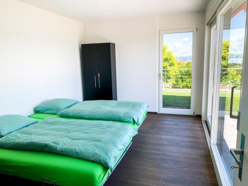 ein Schlafzimmer mit einem grünen Bett und einer Glasschiebetür in der Unterkunft Villa au bord du lac de Morat avec vue imprenable in Bellerive