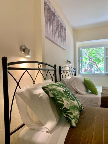 a bedroom with two beds with pillows and a window at Costas Rooms in Aegina Town