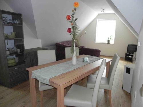 a dining room table and chairs with a vase with flowers at Ferienwohnungen am Unstrutwehr in Freyburg