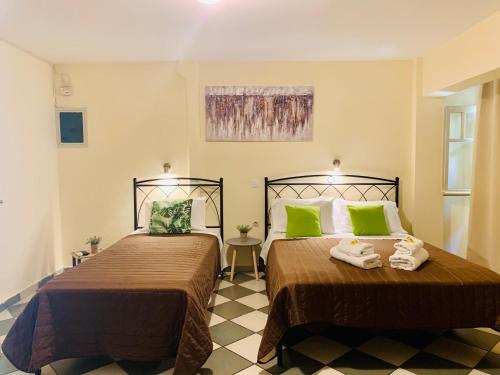 two beds in a room with green pillows at Costas Rooms in Aegina Town