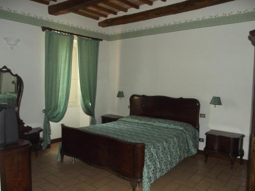 a bedroom with a bed and two windows with green curtains at Agriturismo Villa Gabbiano in Capodacqua