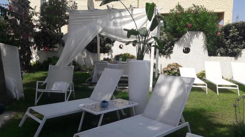 a group of white chairs and tables in a yard at La Casa di Nina in La Maddalena