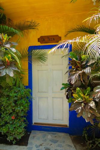 a white door in a yellow building with plants at Balneario y Cabañas ISIS in La Huerta