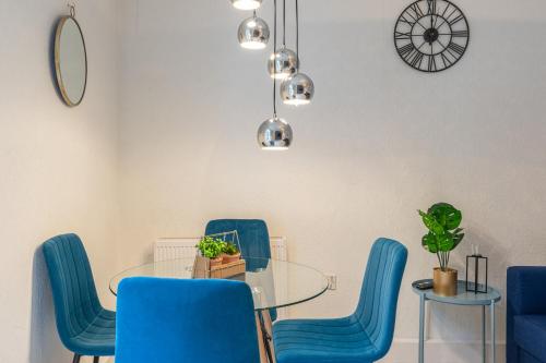 Stunning 2 Bedrooms Apartment Next Door To Selfridges and Oxford Street في لندن: غرفة طعام مع كراسي زرقاء وطاولة زجاجية