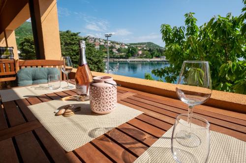 una mesa con una botella de vino y copas en el balcón en Apartmani Suzana, en Klenovica