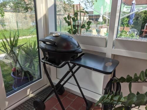 a grill on a stand next to a window at Bonito - Historischer Streckhof in Schützen am Gebirge