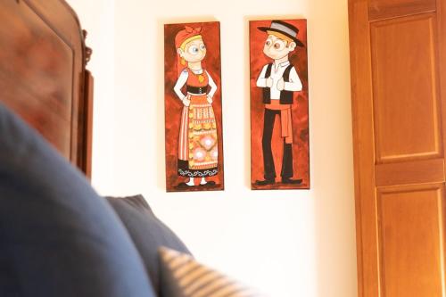 two paintings of a man and a woman on a wall at Recanto do Pinheiro in Arga de Baixo