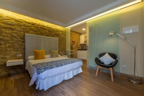 1 dormitorio con 1 cama y 1 silla negra en Apartamentos Praia do Capitàn en Muxía