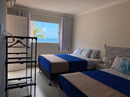 um quarto de hotel com duas camas e uma janela em Pousada A Casa Portuguesa em Cabo de Santo Agostinho