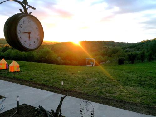une horloge dans un champ avec le soleil en arrière-plan dans l'établissement Sunny Side Fruska Gora -touristic estate, à Velika Remeta