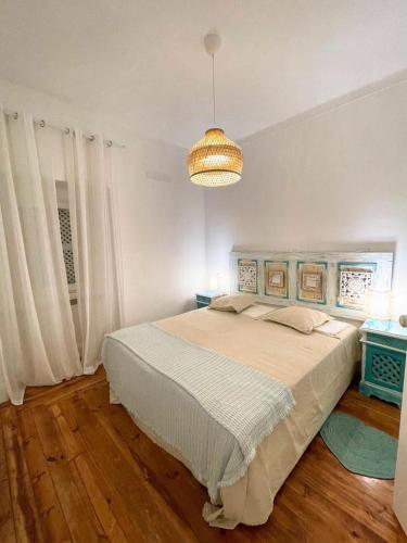 a bedroom with a large bed and a chandelier at 4 Cantos in Faro