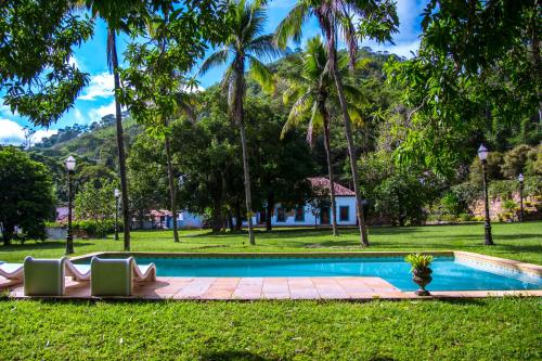 a swimming pool in a park with palm trees at Estancias Duvivier Hotel Fazenda in Três Rios