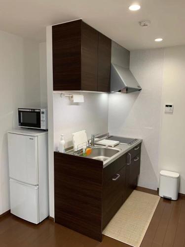 a kitchen with a sink and a microwave and a refrigerator at FunHome Nagoya Castle in Nagoya