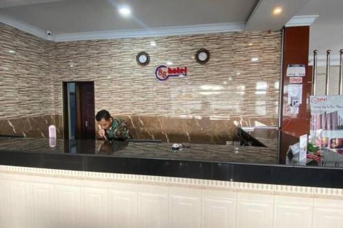 a man sitting at a counter in a restaurant at RedDoorz Plus Syariah @ Jalan Syiah Kuala Banda Aceh in Lheue