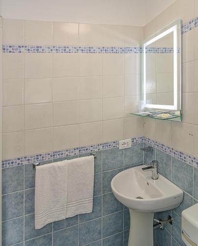 a blue and white bathroom with a sink and a mirror at Hotel Storyville - svago e convenzioni aziendali in Cinquale