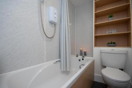 亞伯丁市的住宿－Dwellcome Home Ltd 1 Bed Aberdeen Apartment - see our site for assurance，浴室设有卫生间和带蜡烛的浴缸。
