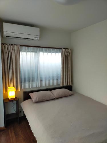a bedroom with a large bed with a window at FunHome Nagoya Castle in Nagoya