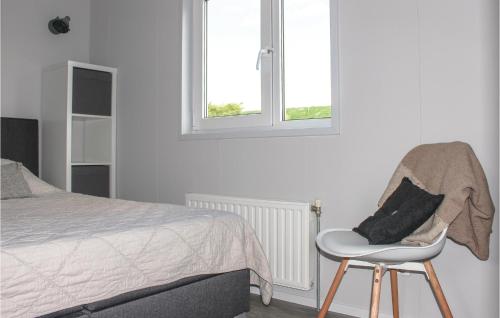 聖安娜蘭的住宿－Beautiful Home In Sint-annaland With Kitchen，一间卧室配有一张床、一把椅子和窗户。