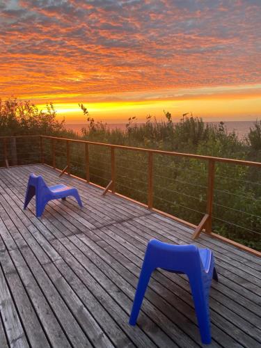 two blue chairs on a deck with a sunset at Bungalows Nadmorska 106 in Sarbinowo