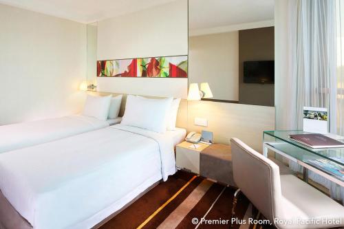 a hotel room with two beds and a glass table at The Royal Pacific Hotel & Towers in Hong Kong