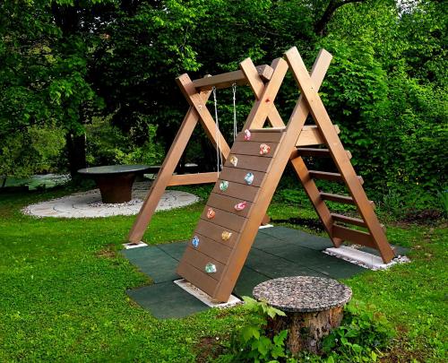 a playground with a wooden ladder and a tree stump at River house HRIB in Preddvor