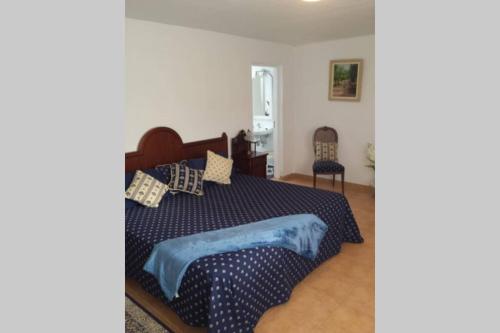 a bedroom with a bed with a blue comforter and two chairs at Los Frailes Eco Finca B in Tinajo