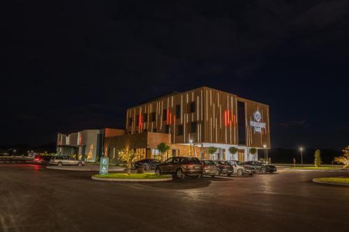 a building with cars parked in a parking lot at night at Hotel President in Čapljina