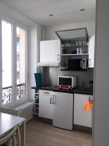 une cuisine avec des armoires blanches et un comptoir noir dans l'établissement Appartement Cosy centre ville Aix les bains (Cures et courts sejours), à Aix-les-Bains