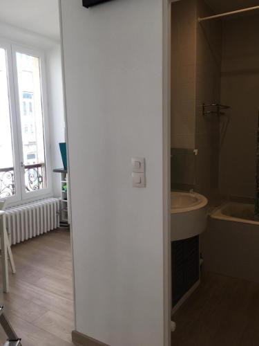 une salle de bain blanche avec un lavabo et une baignoire dans l'établissement Appartement Cosy centre ville Aix les bains (Cures et courts sejours), à Aix-les-Bains