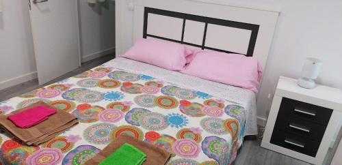 sypialnia z dużym łóżkiem z kolorową pościelą i poduszkami w obiekcie Pisazo calle Peatonal en el centro! w mieście Santander